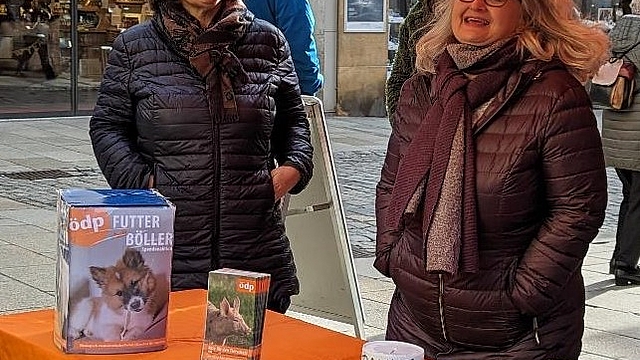 Bild 1: Infostand der ÖDP vom 30. Dezember 2023 für die Aktion "Futter statt Böller". Auf dem Plakat steht geschrieben "Wir verdoppeln ihre Spende". Von links: Anne Schlittmaier und Angela Büchner, dahinter verdeckt Dagmar Murmann-Patzek